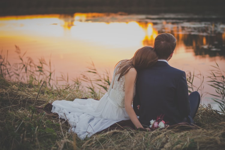 Bride and Groom Sitting on the Edge of a Lake