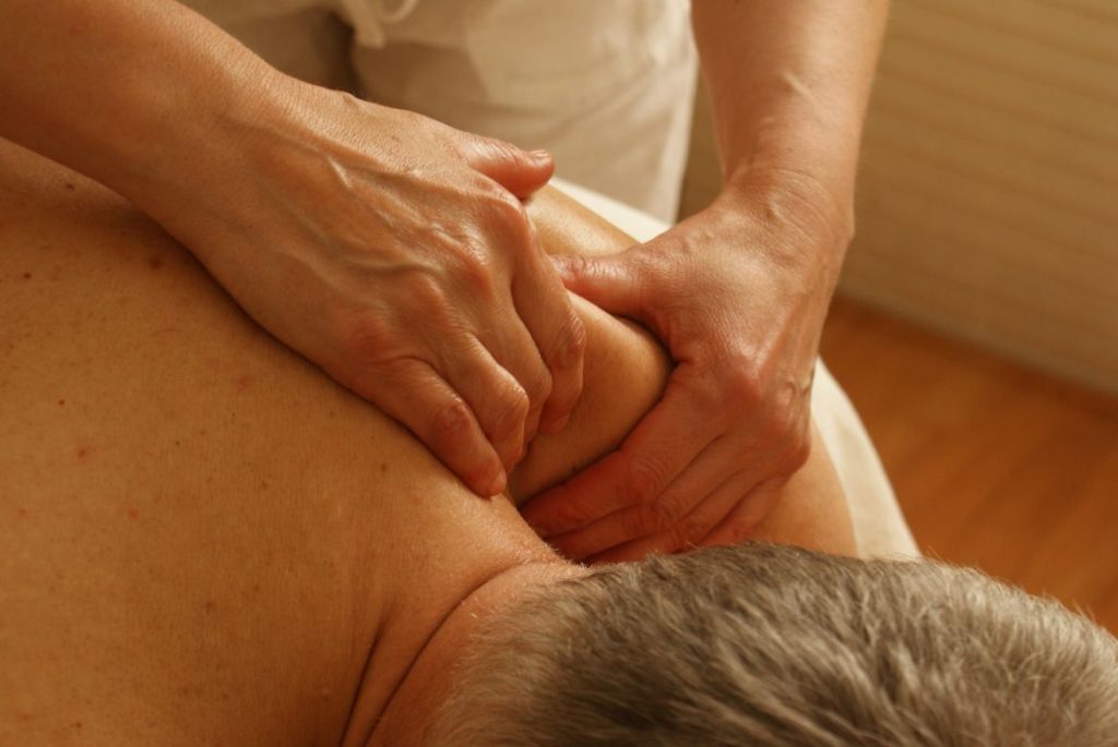 Person massaging the old man's shoulder - Stress Relief Activities | Blurbgeek