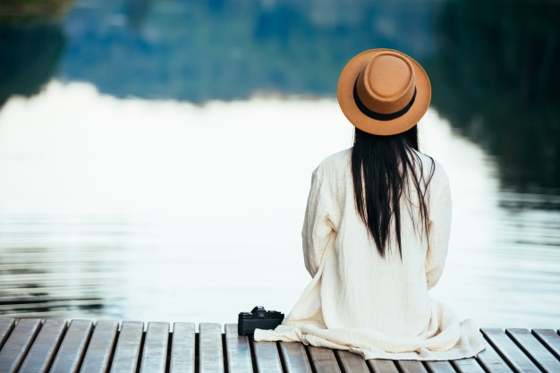 Girl relaxing on waterfront raft - Stress Relief Activities | Blurbgeek 