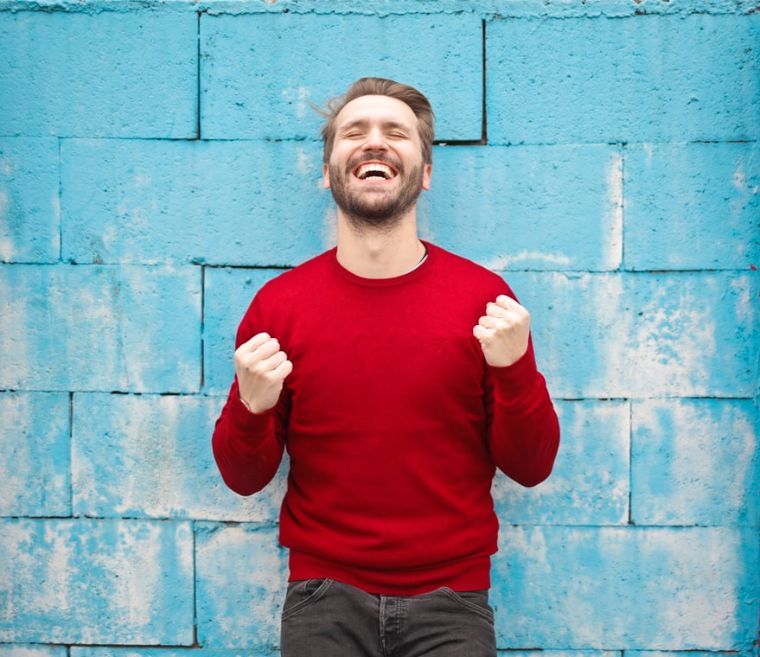 A happy man standing in-front of the wall | Stress Relief Activities | Blurbgeek 