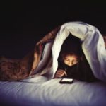 Girl using phone in dark with excessive brightlight